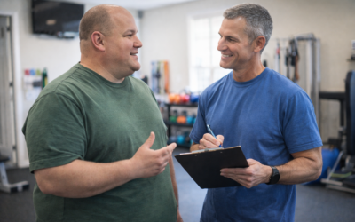Two men engaged in a conversation in a gym setting, one providing guidance as a personal trainer, emphasizing personalized fitness and motivation.